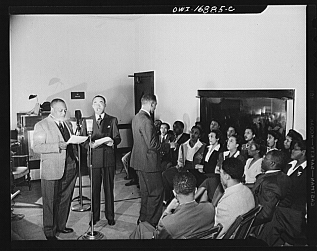 Wings over Jordan, a popular Sunday morning radio program broadcast by Columbia Broadcasting System from station WDBO. In front of the microphone are Glenn Settle and James Colston while the singers remain seated.