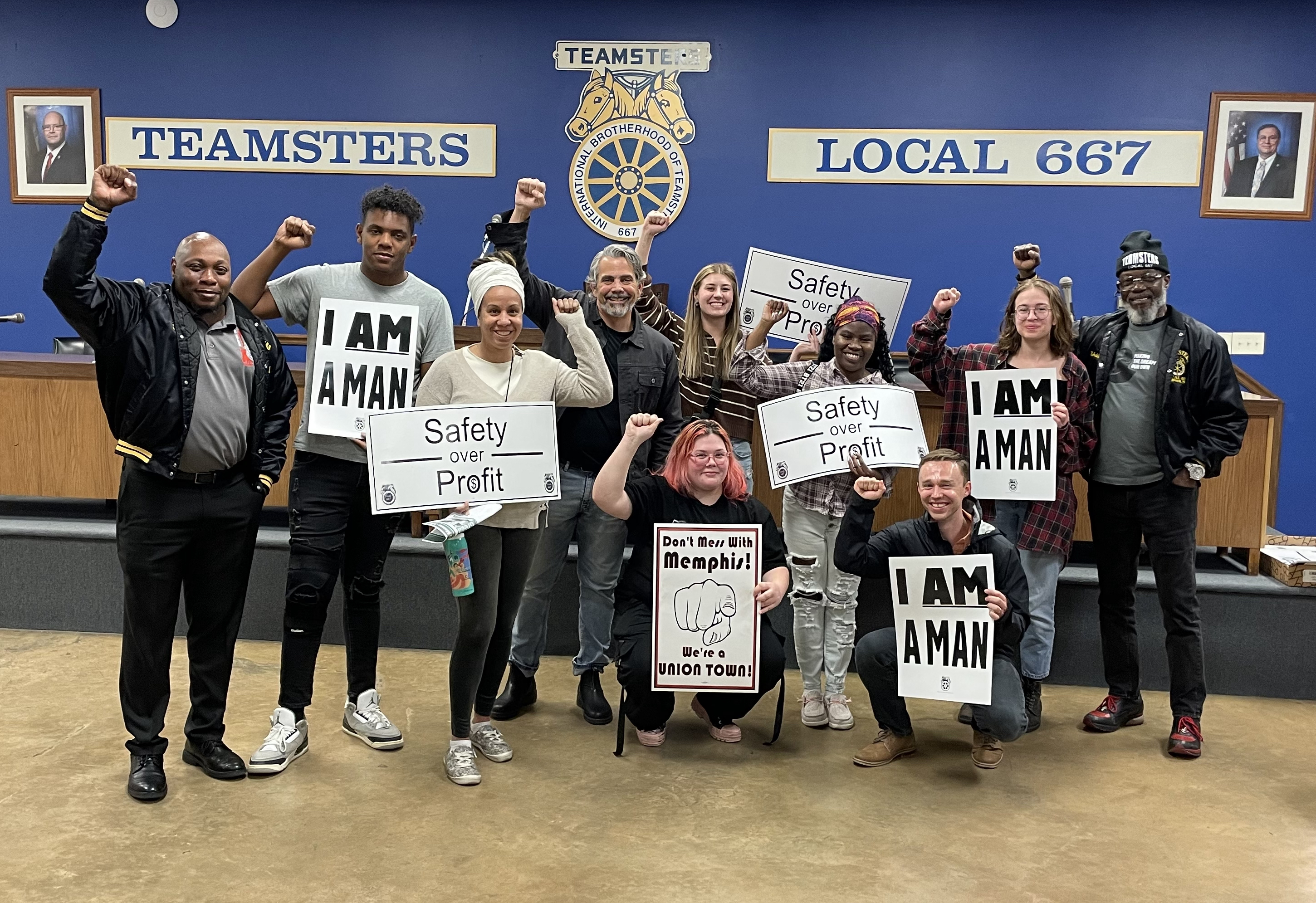 Photo of American Culture Program students and faculty with leaders of the Memphis union. All pictured are raising their fists and many are holding signs that say things such as I Am a Man or Don't Mess with Memphis